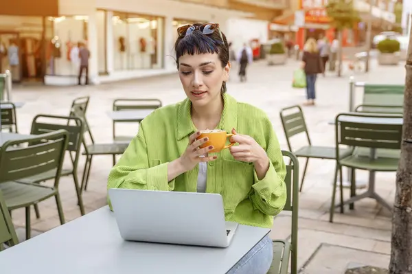 woman having coffee at the street cafe outside, talking on the laptop and having fun time. lifestyle concept