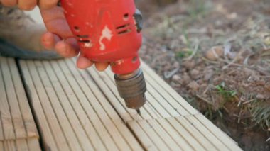 Erkek müteahhit kerestelerin vidalarını sökmek için matkap kullanıyor.