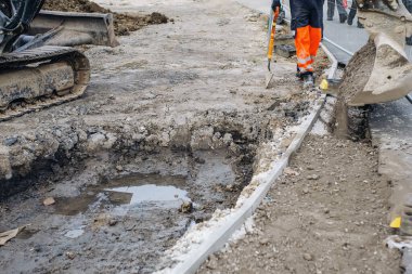A new footpath is under construction as builders bring stone, levelling and compacting it