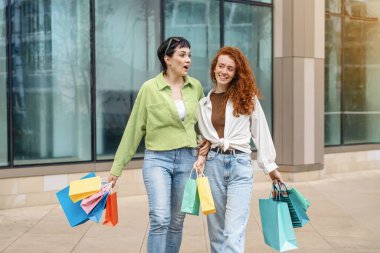 Renkli çantalı kadınlar şehir merkezinde alışveriş yaparken eğleniyorlar. Tüketim, satış, alım, alışveriş, yaşam tarzı konsepti.