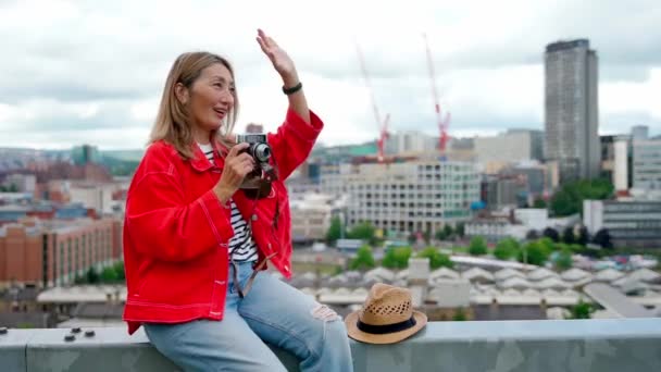 快乐的亚洲女人穿着红色夹克坐在谢菲尔德前 在夏日拍照 — 图库视频影像