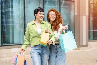 Renkli çantalı kadınlar şehir merkezinde alışveriş yaparken eğleniyorlar. Tüketim, satış, alım, alışveriş, yaşam tarzı konsepti.