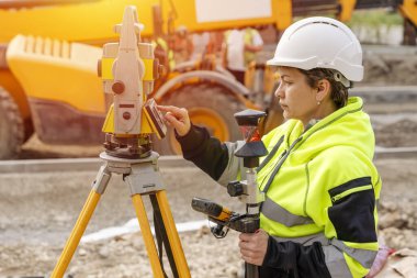 Bir inşaat şantiyesinde Theodolite toplam EDM ekipmanıyla çalışan bir kadın inşaat mühendisinin yakın plan portresi.