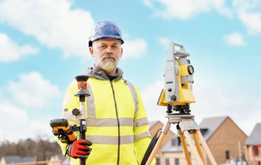 Surveyor builder site engineer with theodolite total station at construction site outdoors during surveying work clipart