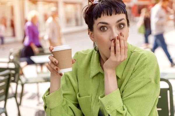 surpraised woman having coffee at the street cafe outside, talking with friend aand in shock from information,  having fun time. lifestyle concept