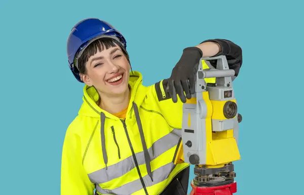 Smiling Woman in hard hat and protective clothes land surveyor working with modern surveying geodesic instrument tachometer checking coordinates. Young woman working in construction industry