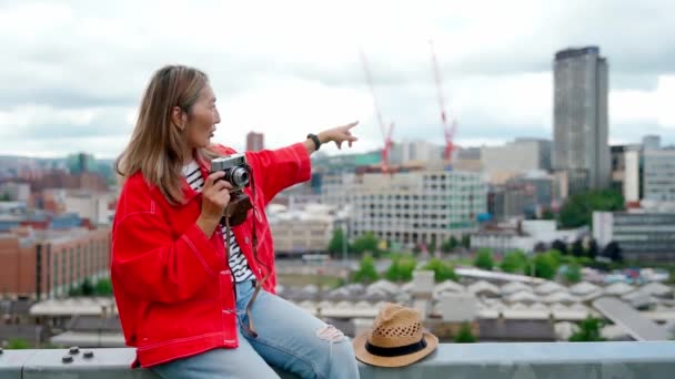 Щаслива Азіатська Жінка Червоній Куртці Сидить Перед Містом Шеффілд Фотографується — стокове відео
