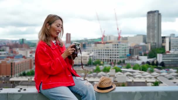 シェフィールドの前に座って 素晴らしい夏の日に写真を撮る赤いジャケットの幸せなアジアの女性 — ストック動画