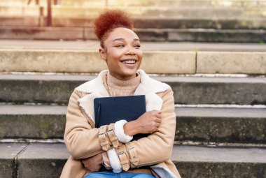 Olumlu Afrikalı Etnik Kadın 'ın öğrenmesi, okuması, okuması şehrin merdivenlerinde oturması hoşuma gitti. Eğitim kavrayışı