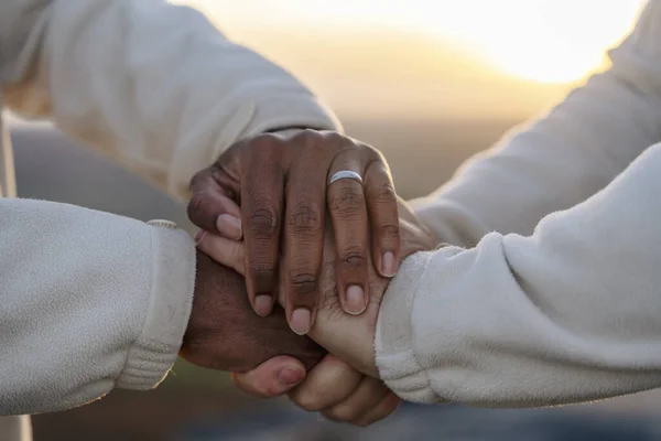 Close up of a black and white hands holding each other in nature at sunset. Happy gay couple holding hands watching sunset