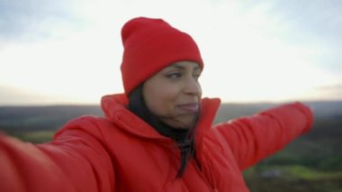 Sırt çantasıyla gezen ve İngiltere 'de gün batımında dağların tadını çıkaran gülümseyen güzel bir turist kadın. Sırt çantasıyla dağlara bir gezi.