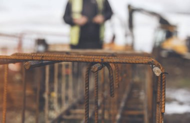 Bir işçi demir çubukları birbirine bağlamak için çelik teller kullanır. Güçlendirilmiş beton yapılar. Beton kiriş için çelik bir kafes yapıyorlar.