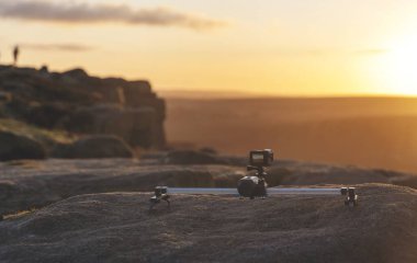 Adam zaman çizelgeleri çekmek için dağda yürüyüş yapıyor ya da kamera önünde gündoğumunun videosunu çekiyor.