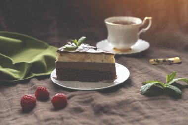 Beyaz tabakta çikolatalı kek ve çilekli çay.