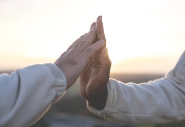 Gün batımında beyaz adam ve siyah Afrikalı Amerikalı adamın elleri yavaşça ve nazikçe birbirine dokunuyor. Irkçılık ve dostlukla mücadele kavramı imajını yumuşattı.