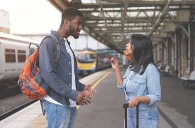 Kadın ve erkek tren bekliyor ve tren istasyonunda konuşuyorlar.