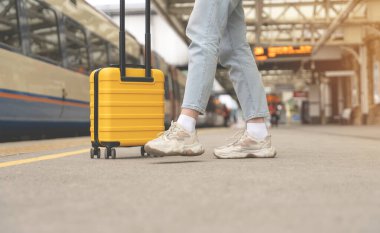 Sarı valizli gezginler, turuncu sırt çantalı tren istasyonunda tren bekliyor. Seyahat kavramı.