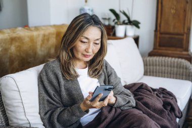 Asyalı kadın evde harika zaman geçiriyor kahve içiyor, sıcak çikolata içiyor, çay içiyor, müzik dinliyor, ailesiyle iletişim kuruyor. Yaşam tarzı kavramı