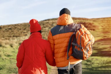 Gün batımında kırsal alanda yürüyen mutlu bir çiftin portresi. Aşk, yürüyüş ve aktif yaşam tarzı konsepti