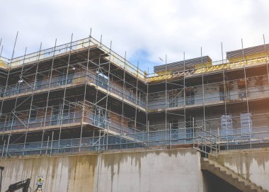 İşyeri, pencereler ve çatı kurulumuna güvenli erişim sağlamak için yeni bir yerleşim alanının etrafına yeni bir çok katlı tuğla ev inşa edildi.