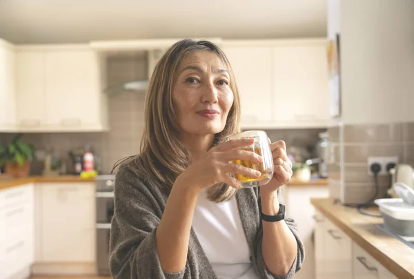 Asian woman spending great time at home drinking coffee, hot chocolate, tea, listening to music, communicating with family. Lifestyle concept