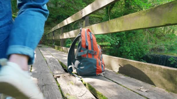 橘色背包在防止瀑布的旧桥上 旅行概念 — 图库视频影像
