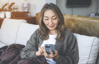 Asyalı kadın evde harika zaman geçiriyor kahve içiyor, sıcak çikolata içiyor, çay içiyor, müzik dinliyor, ailesiyle iletişim kuruyor. Yaşam tarzı kavramı
