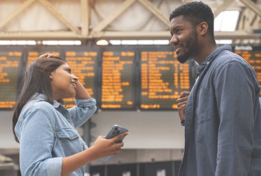 Bir grup çok ırklı arkadaş trene binmeden önce tren istasyonundaki kalkış saatlerini kontrol ediyor. Tren konseptiyle seyahat etmenin keyfini çıkarıyorum.