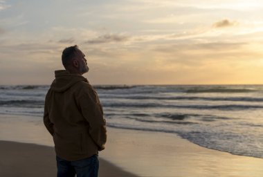 Sakallı Adam gün batımında sıcak güneşli bir günde deniz kenarında tek başına dinleniyor. Seyahat yaşam tarzı konsepti