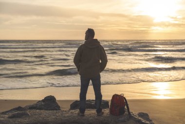 Sakallı Adam gün batımında sıcak güneşli bir günde deniz kenarında tek başına dinleniyor. Seyahat yaşam tarzı konsepti