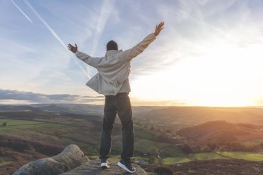 Sırt çantasıyla gezen ve İngiltere 'de gün batımında dağların tadını çıkaran yakışıklı turist. Sırt çantasıyla dağlara bir gezi. Yürüyüşün ve yeni yerler keşfetmenin tadını çıkarın.