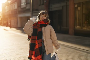 Mutlu genç kız öğrenci gülümsüyor ve gün batımında şehirde dolaşıyor.