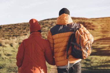 Gün batımında kırsal alanda yürüyen mutlu bir çiftin portresi. Aşk, yürüyüş ve aktif yaşam tarzı konsepti görüntüyü yumuşattı