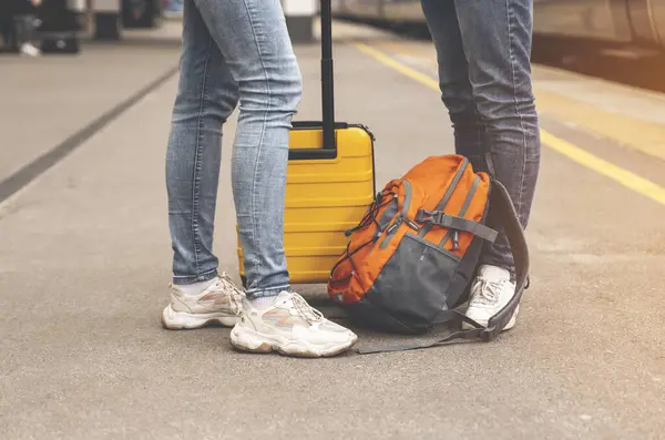 a couple, friends traveling together, waiting for train on a platform with luggage. Traveling together concept