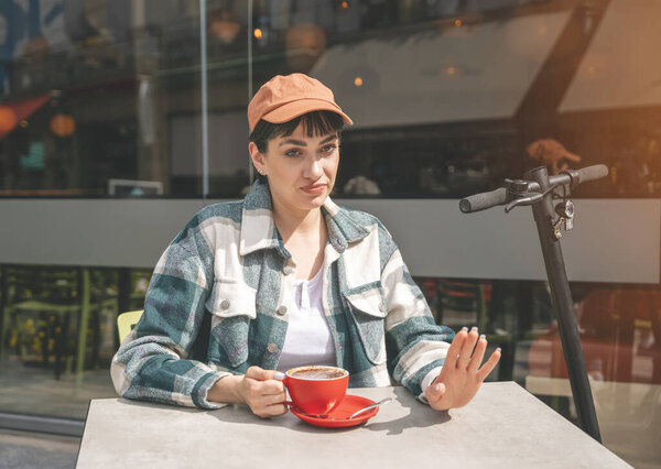 displeased woman having coffee at the street cafe with friend outside, showing  sign stop,  lifestyle concept Negative  human expression and body language concept