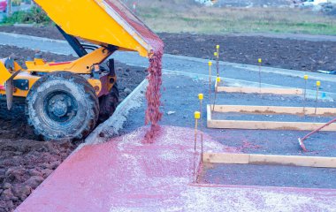 Yeni yürüme yolu inşaatı sırasında ıslak hazır-karıştırılmış betonu döken ve döken inşaatçılar