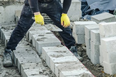 Yeni yerleşim alanının beton zemin kirişinin üzerine beton bloklar döşeyen çok çalışan bir duvarcı. Konut kriziyle daha ekonomik konutlar inşa ederek savaşın