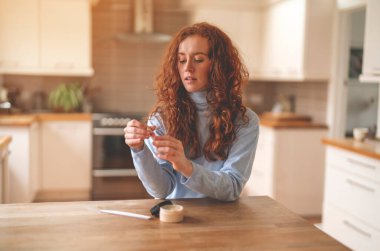 Kadın bej rujla dudak boyuyor. Elinde küçük bir ayna. Bakım ve makyaj konsepti, yaşam tarzı ve güzellik. Tonu ayarlanmış resim.