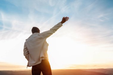Sırt çantasıyla gezen ve İngiltere 'de gün batımında dağların tadını çıkaran yakışıklı turist. Sırt çantasıyla dağlara bir gezi. Yürüyüşün ve yeni yerler keşfetmenin tadını çıkarın.