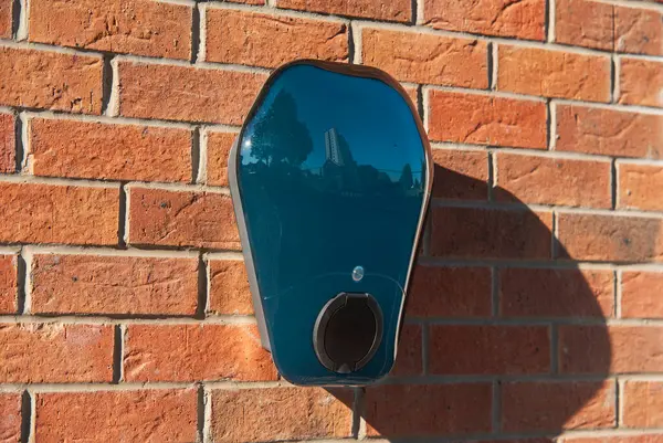 Private electric vehicle charging station fitted to the face of a red brick wall