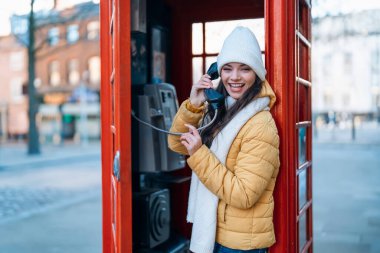 Outdoor portrait of woman using camera against red phonebox in English city
