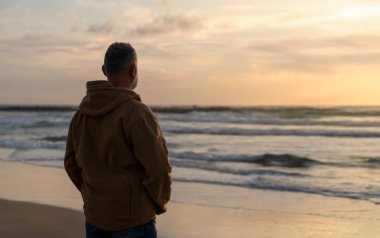 Sakallı Adam gün batımında sıcak güneşli bir günde deniz kenarında tek başına dinleniyor. Seyahat yaşam tarzı konsepti
