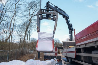 Dropside plakalı HIAB vinç kamyonu tuğla kapma eklentisiyle inşaat alanına malzeme getiriyor ve indiriyor.