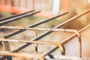 Bir işçi demir çubukları birbirine bağlamak için çelik teller kullanır. Güçlendirilmiş beton yapılar. Beton kiriş için çelik bir kafes yapıyorlar.