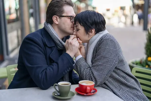Handsome man and beautiful woman falling in love, hugging each other, sitting in the cafe as they walk around a city, having a fun time, lifestyle photo