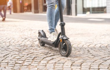 Şehirdeki insanların yaşam tarzı konseptinde kadın bacaklarını elektrikli scooterla kapatın.