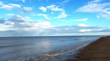 Kumsal, deniz ve bulutlu mavi gökyüzü güneşli bir günde İngiltere 'de