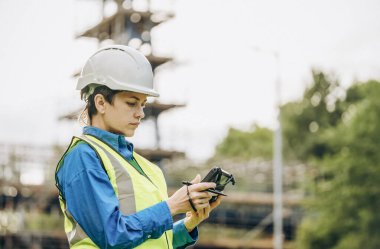 Bir inşaat şantiyesinde Theodolite toplam istasyon EDM ekipmanıyla çalışan kadın inşaat mühendisi araştırmacısı.