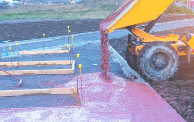 Yeni yürüme yolu inşaatı sırasında ıslak hazır-karıştırılmış betonu döken ve döken inşaatçılar