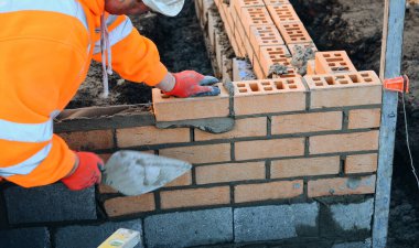 Close up of industrial bricklayer laying bricks on cement mix on construction site